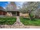 Charming brick home with a lush green lawn and a blossoming tree in the front yard at 1865 S Logan St, Denver, CO 80210