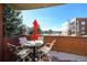 Inviting balcony with brick surround featuring table, chairs and red umbrella at 4875 S Monaco St # 103, Denver, CO 80237