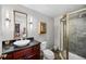 Well-lit bathroom featuring a tiled shower, dark vanity, and decorative mirror at 4875 S Monaco St # 103, Denver, CO 80237