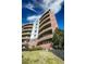 View of multi-story building with curved balconies and red brick facade, enhanced by green landscaping at 4875 S Monaco St # 103, Denver, CO 80237