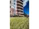 Multi-story red brick building with unique curved balconies, set against a lush green lawn at 4875 S Monaco St # 103, Denver, CO 80237