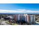 Brick apartment building with mountain views, mature trees and a blue sky background at 4875 S Monaco St # 103, Denver, CO 80237