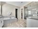 Bright bathroom featuring herring bone floors, soaker tub, double vanity, glass enclosed shower, and walk in closet at 8661 S De Gaulle Ct, Aurora, CO 80016