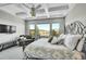 Bright main bedroom featuring coffered ceilings, chandelier, iron bed frame, sitting area and large windows with scenic views at 8661 S De Gaulle Ct, Aurora, CO 80016