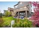 Backyard view of a two-story home with a deck, covered patio, stone pillars, and landscaping at 14807 Haley Ave, Parker, CO 80134
