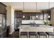 Contemporary kitchen boasts dark cabinets, stainless steel appliances, a granite island with seating, and stylish pendant lighting at 14807 Haley Ave, Parker, CO 80134