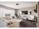 Bright living room featuring hardwood floors, a stylish fireplace, a large window with sheer white curtains, and modern furnishings at 14807 Haley Ave, Parker, CO 80134