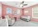 This Bedroom features pink walls, a crib, a rocking chair, and a ceiling fan, making it a cozy and inviting space at 12759 Buffington Trl, Parker, CO 80134