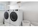 Well-lit laundry room featuring a modern washer and dryer set, shelf and organizing bins for storage with a gray rug at 12759 Buffington Trl, Parker, CO 80134