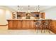 Basement bar with wood cabinetry, granite countertops, and barstool seating at 27 Tamarade Dr, Littleton, CO 80127