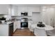 Modern kitchen featuring white cabinetry, stainless steel appliances, granite countertops, and an adjacent breakfast area at 46558 Avery Ln, Bennett, CO 80102