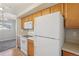 Functional kitchen featuring wood cabinets and white appliances near a sunlit room at 5726 N Genoa Way # 301, Aurora, CO 80019