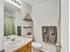 Clean bathroom with light wood cabinets, decorative shelves, and plush gray towels at 6414 Stuart St, Arvada, CO 80003
