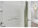 Clean bathroom features a white tiled tub/shower with a green shower curtain and an open doorway at 6414 Stuart St, Arvada, CO 80003