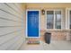 Charming front porch featuring a bright blue front door, sidelight window, and a welcome mat, creating a friendly entrance at 6414 Stuart St, Arvada, CO 80003
