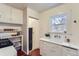 This kitchen features white cabinetry, an oven range, open shelving, and a classic sink basin with a window at 109 W Simpson St, Lafayette, CO 80026