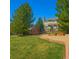 Spacious backyard featuring a well-maintained lawn, garden beds, mature trees, and a fenced perimeter at 7661 Chickaree Ct, Littleton, CO 80125
