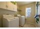 Functional laundry room with washer, dryer, and storage cabinets, making laundry day a breeze at 7661 Chickaree Ct, Littleton, CO 80125