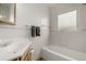 An all-white bathroom features a shower-tub combo, a sink with wooden cabinetry, and tile flooring at 1386 S Garfield St, Denver, CO 80210