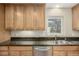 A kitchen sink features wooden cabinets, granite countertops, stainless steel dishwasher, and a garden view at 1386 S Garfield St, Denver, CO 80210