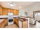 Open kitchen with wood cabinets, standard appliances, and seamless flow to the living room at 2116 W 101St Cir, Thornton, CO 80260