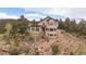 Exterior of home featuring a lush landscape and stone patio overlooking the serene mountain scenery at 23007 Big Game Trl, Conifer, CO 80433