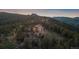 Scenic view of a home surrounded by trees, featuring manicured landscaping and mountain views at 23007 Big Game Trl, Conifer, CO 80433