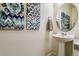 Stylish powder room features decorative paintings, a pedestal sink, and a round mirror at 3218 Belleville Ridge Rd, Elizabeth, CO 80107