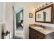Well-lit bathroom featuring a large vanity with granite countertop, mirror, and adjacent bedroom space at 7792 Garrison Ct, Arvada, CO 80005
