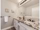 Bathroom with dual sinks, granite counters, oversized mirror, tile backsplash, and modern fixtures for a clean, updated look at 7792 Garrison Ct, Arvada, CO 80005