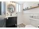 Stylish powder bathroom with black vanity, decoratively tiled floor, and open shelf with decorative items at 17067 Motsenbocker Way, Parker, CO 80134