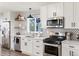 Modern kitchen with white cabinets, stainless steel appliances, geometric backsplash, and floating shelves at 17067 Motsenbocker Way, Parker, CO 80134