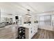 Bright kitchen with white cabinets and an island, offering seating and seamless flow to the living room and outdoor patio at 17067 Motsenbocker Way, Parker, CO 80134