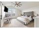 Airy primary bedroom with vaulted ceiling, large windows, ceiling fan, tufted headboard and soft neutral carpet at 17067 Motsenbocker Way, Parker, CO 80134