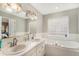 Bright bathroom with a double sink vanity, large mirror and tub with tiled wall and a glass block window at 6657 Drew Ranch Ln, Boulder, CO 80301