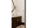 Modern bathroom with dark vanity, gold hardware, statement mirror and natural stone flooring at 3 Carriage Brook Rd, Cherry Hills Village, CO 80121