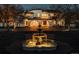 Dramatic night view of a luxurious estate highlighting a lighted fountain and a beautifully illuminated home at 3 Carriage Brook Rd, Cherry Hills Village, CO 80121