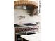 Close up of the gourmet kitchen with brick stove hood, marble backsplash and chef's range at 3 Carriage Brook Rd, Cherry Hills Village, CO 80121