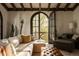 Inviting living room features exposed beam ceilings, large arched door to balcony, and plush seating at 3 Carriage Brook Rd, Cherry Hills Village, CO 80121