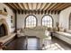 Sunlit living room featuring a fireplace, exposed beams, grand piano, and arched windows at 3 Carriage Brook Rd, Cherry Hills Village, CO 80121