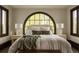 Serene main bedroom features a large arched window, plush bedding, and stylish bedside lamps at 3 Carriage Brook Rd, Cherry Hills Village, CO 80121