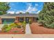 Charming brick home features a beautifully landscaped front yard with colorful flowers and mature trees at 3049 S Williams St, Denver, CO 80210