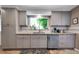 Kitchen featuring tile backsplash, garden window above sink, and stainless appliances at 3049 S Williams St, Denver, CO 80210