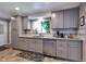 Bright kitchen with stainless dishwasher and sink under window and gray cabinets at 3049 S Williams St, Denver, CO 80210