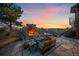 Inviting back patio with a stone fireplace, seating, and sunset views perfect for outdoor entertaining at 1159 Buffalo Ridge Rd, Castle Pines, CO 80108
