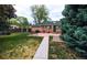 Lush backyard with a brick patio, grill, green grass, and mature trees providing shade at 2592 S Winona Ct, Denver, CO 80219