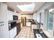 Bright kitchen featuring white cabinets, stainless steel appliances, and skylight for natural lighting at 2592 S Winona Ct, Denver, CO 80219