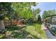Lush backyard featuring a manicured lawn, mature trees, a wood fence, and a cozy seating area at 11279 E Alaska Pl, Aurora, CO 80012