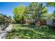 Spacious backyard with lush lawn, mature trees, and a charming fence, perfect for outdoor activities at 11279 E Alaska Pl, Aurora, CO 80012