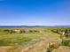 Expansive aerial view of open fields, mountains, and a distant neighborhood with a clear blue sky at 5090 Golden Valley Trl, Castle Rock, CO 80109